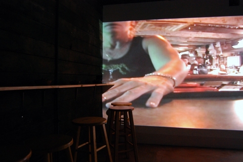 The Last Resort - Installation View, Krowswork Gallery - Oakland, CA Cybele Lyle The Last Resort at Krowswork Gallery Video Projection, Wood Stools, Wood Bar, Mirrored Plexi, Dart Board, Red Light, Beer