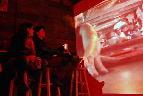 The Last Resort - Installation View, Krowswork Gallery - Oakland, CA Cybele Lyle The Last Resort at Krowswork Gallery Video Projection, Wood Stools, Wood Bar, Mirrored Plexi, Dart Board, Red Light, Beer