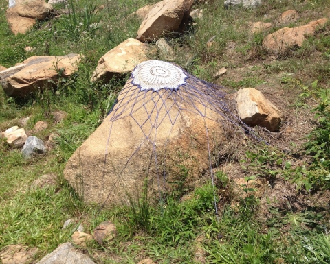 Dwell s i t e specific one dozen cotton doilies stretched over found rocks